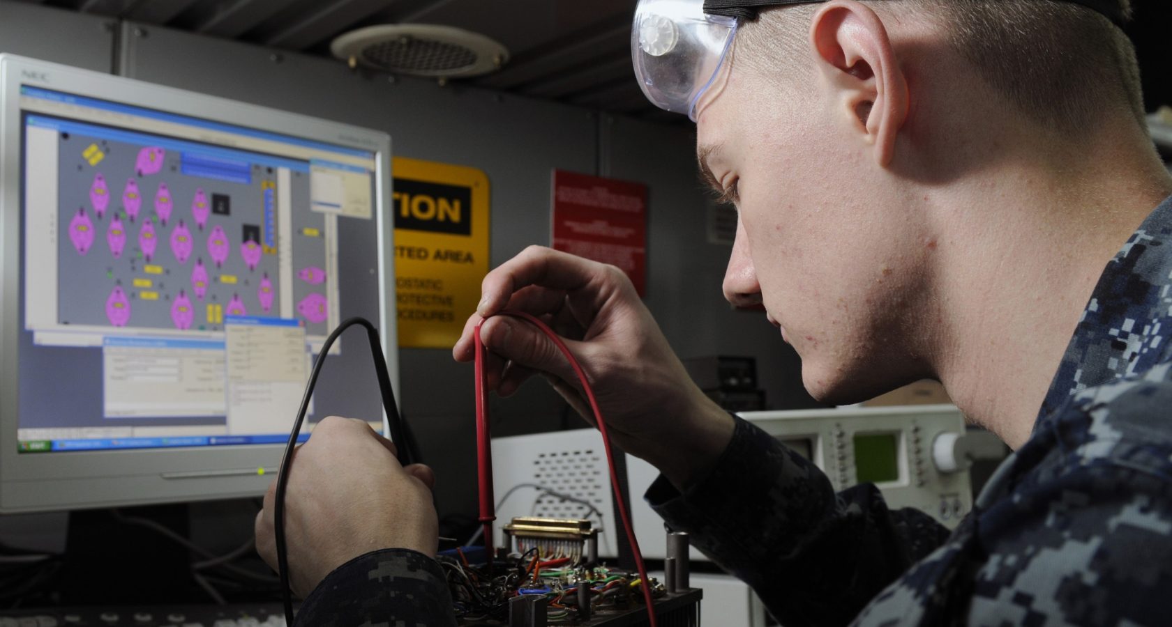Electronics technician testing the connectivity of a circuit board with multimeter probes
